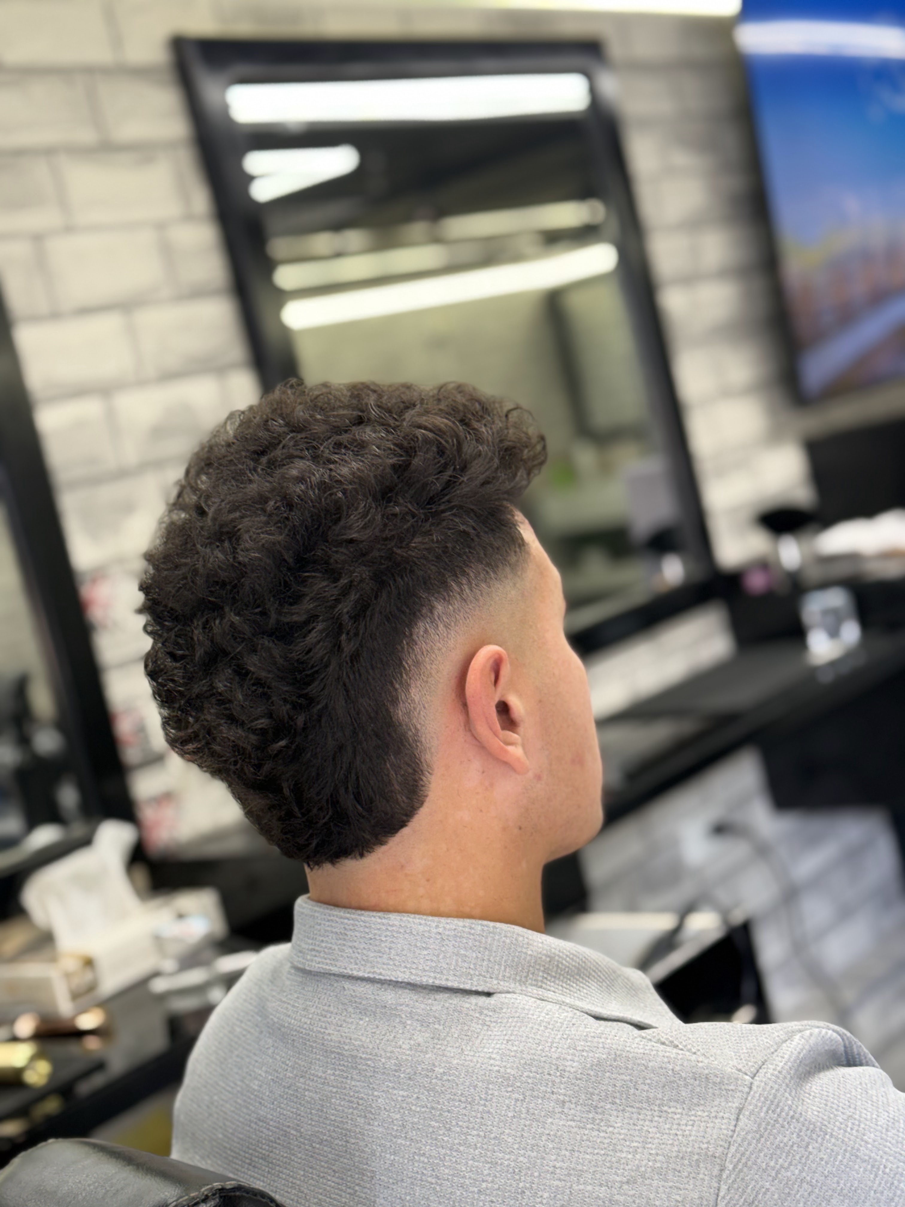 Finished curly-top skin fade, viewed from behind at Salon Owais