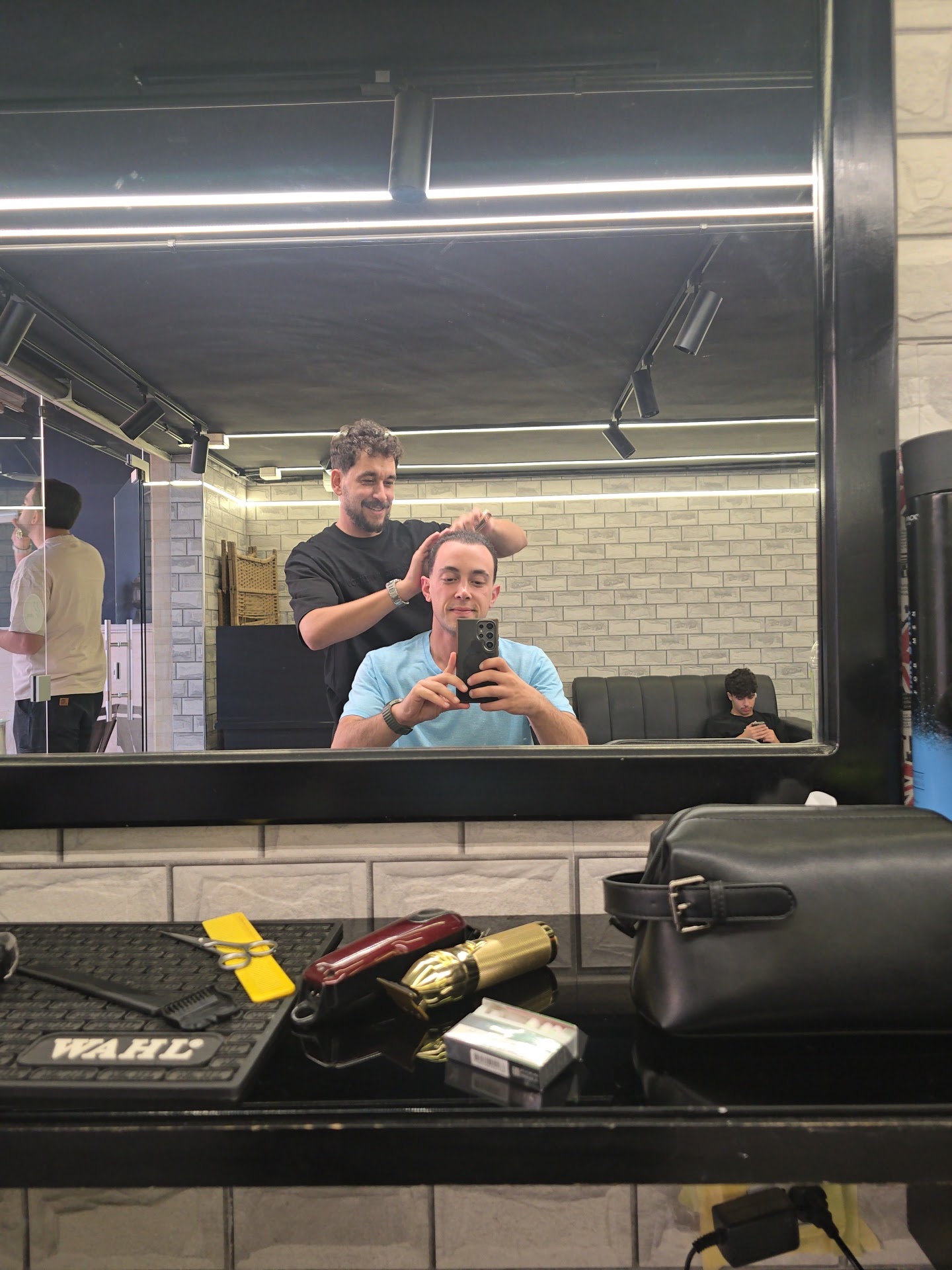 Barber styling a client's hair at Salon Owais, tools laid out on the station